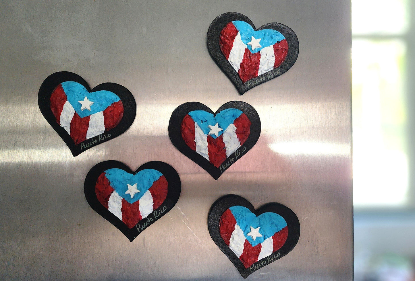 Four heart-shaped patches with a Puerto Rican flag design on a metallic surface.
