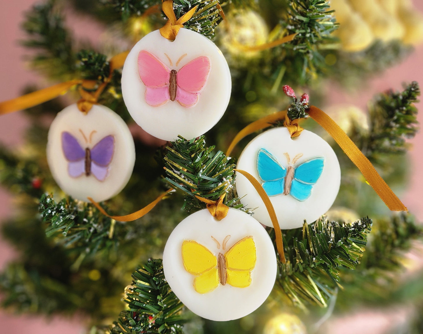 Wax Butterfly-themed Christmas ornaments on a tree with a pink background