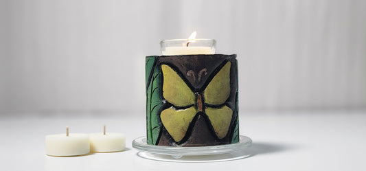 Candle in a decorative holder with butterfly design on a white background