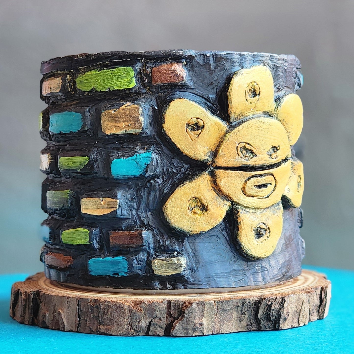 Ceramic sculpture with a Colorful brick-patterned design on a wooden base against a gray background